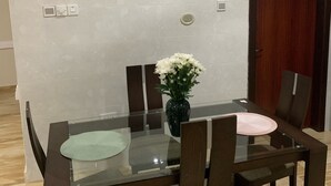 A dining area with a glass table, wooden chairs, a vase with flowers, and a painting on the wall. - Modern and Spacious 2 Bdrm Serviced Apt w/ Patio - Approx. 15 mins from Airport (Accra)