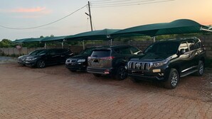 A parking area with several SUVs parked under green umbrellas. - Modern and Spacious 2 Bdrm Serviced Apt w/ Patio - Approx. 15 mins from Airport (Accra)