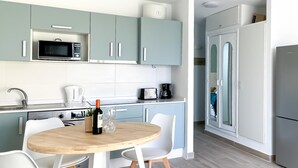 A modern kitchen with teal cabinets, a microwave, a coffee maker, and a wine bottle on the counter. - Casa Bella by Best Holidays Fuerteventura (Corralejo)