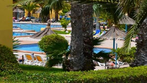 A pool area with lounge chairs and palm trees. - Casa Bella by Best Holidays Fuerteventura (Corralejo)