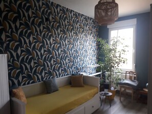 A living room with a patterned wall, a sofa, a small table, and a chair.