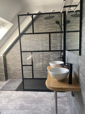 Ein modernes Badezimmer mit Oberlicht, einem Holzbadezimmermöbel mit zwei Waschbecken und einer schwarzen Metallabtrennung.