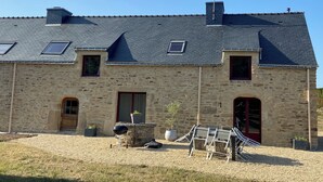 A stone building with a sloped roof, multiple windows, and a chimney. - Gite de Kerguen (Landaul)