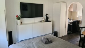 Ett modernt hotellrum med en säng, en tv som är monterad på väggen, ett litet pentry och ett badrum.