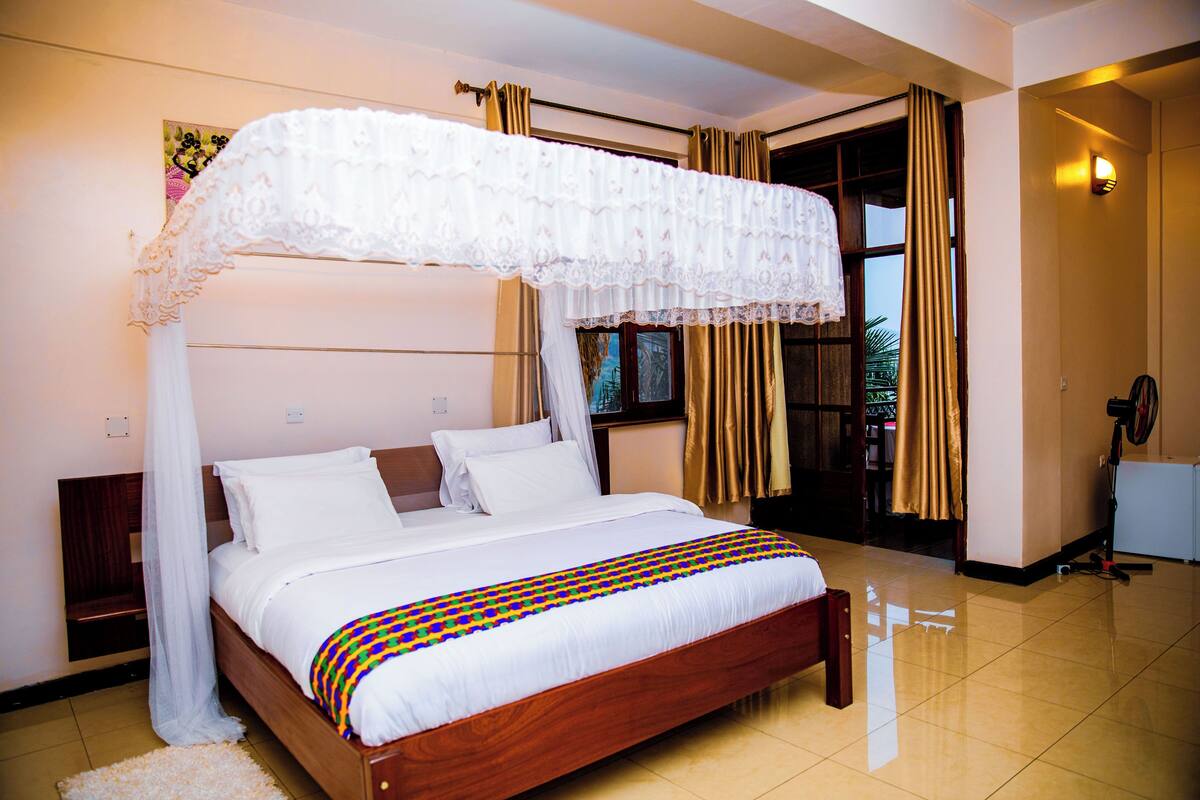 A spacious bedroom with a large bed, a canopy, and a view of the outdoors.