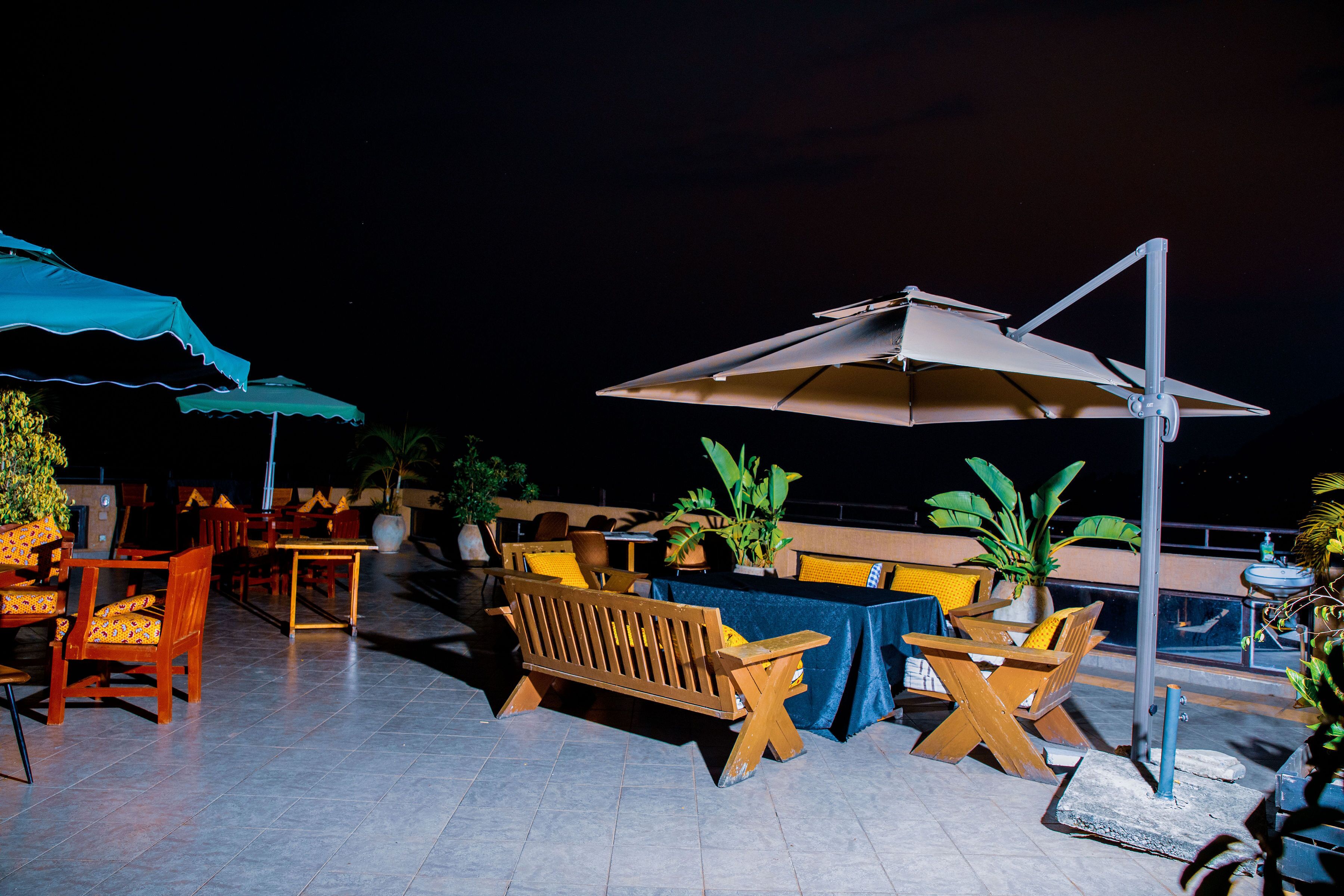 An outdoor patio area with wooden furniture, umbrellas, and potted plants.