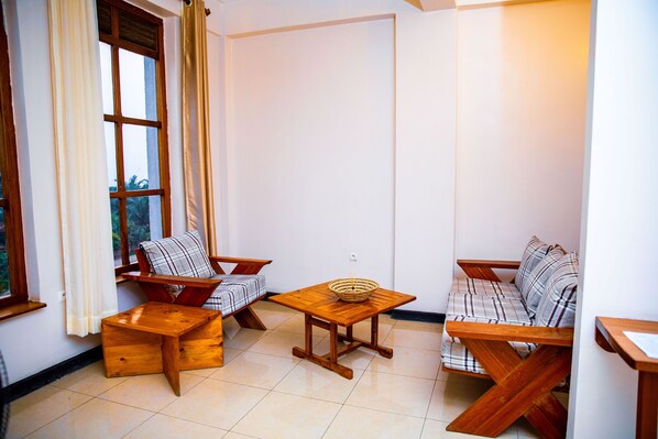 Une pièce chaleureuse avec un canapé en bois, un fauteuil assorti et une petite table en bois.
