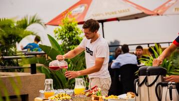 A breakfast buffet with various food items and a person pouring a drink.