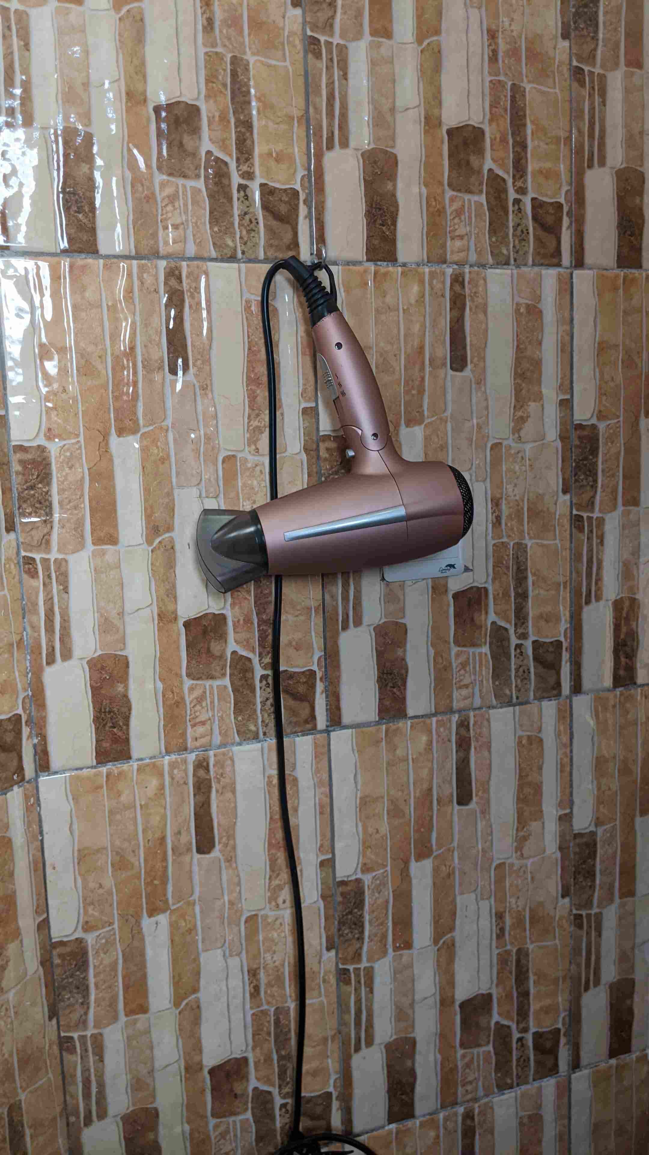 A hairdryer mounted on a tiled wall.