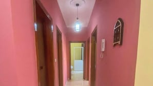 A hallway with pink walls, white tiled flooring, and doors leading to other rooms. - Apartment 2 Agadir (Agadir)