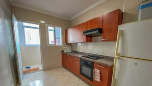 Une cuisine avec des meubles de rangement en bois, une cuisinière et un réfrigérateur.
