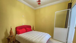 Ein Schlafzimmer mit einem Bett, einem Nachttisch, einem Spiegel und einer Tür.