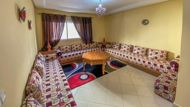 Ein Wohnzimmer mit einem großen, winkelförmigen Sofa, einem runden Couchtisch und einer Kronleuchter.
