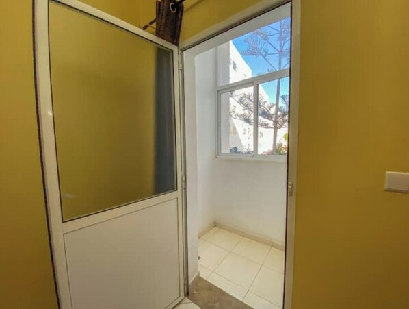 A narrow hallway with a window leading to an outdoor area.