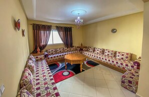 A living room with a large L-shaped sofa set, a round coffee table, and a chandelier.