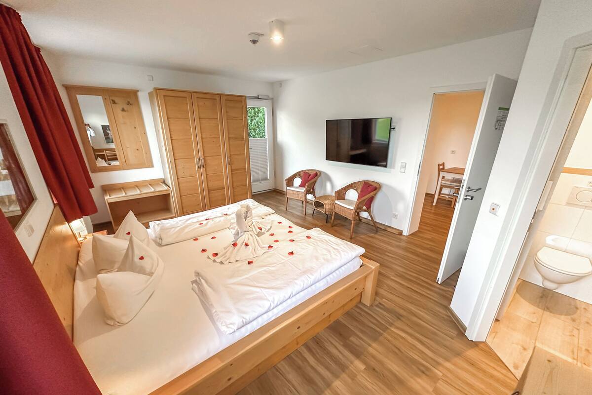 A bedroom with a wooden bed, a TV, a wardrobe, and a bathroom.
