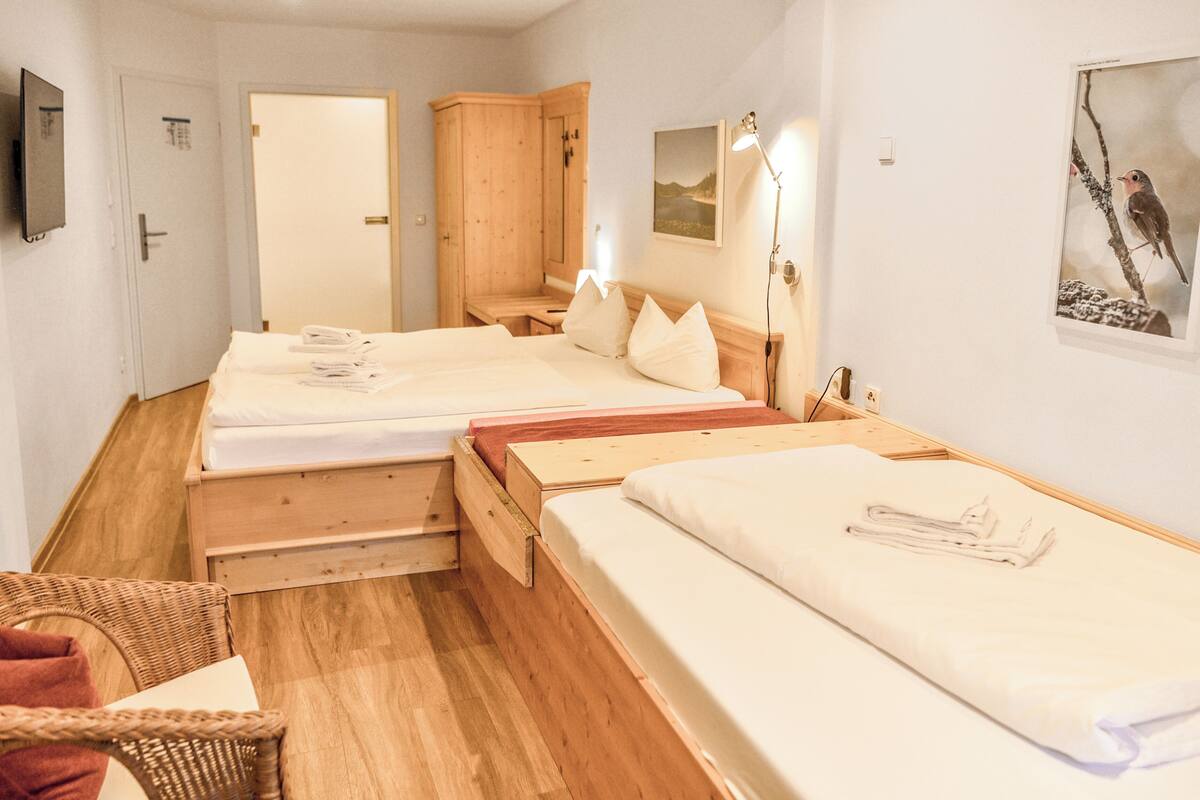 A hotel room with two beds, wooden furniture, a TV, and a painting of a bird.