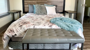 Een slaapkamer met een bed, een bankje en een hoofdeinde.