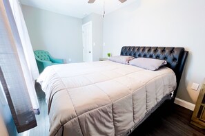 A bedroom with a bed, a chair, and a door. - The Haines Villa (Niagara Falls)