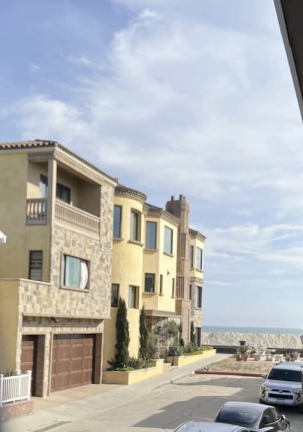Un edificio residencial de varios pisos con fachada de piedra, varios balcones y un garaje.