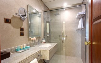 Un baño moderno con cabina de ducha de vidrio, tocador con lavamanos y un espejo grande.