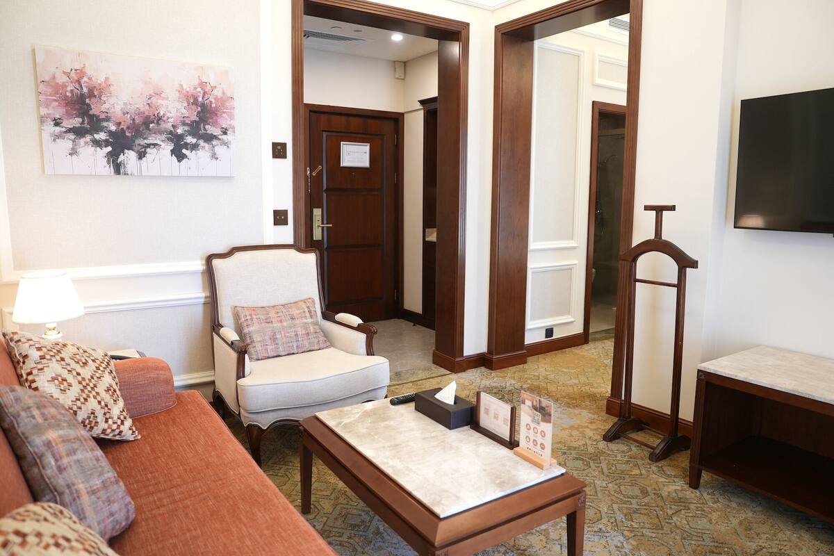 Una sala de estar con sofá, sillón, mesa de centro y un cuadro en la pared.
