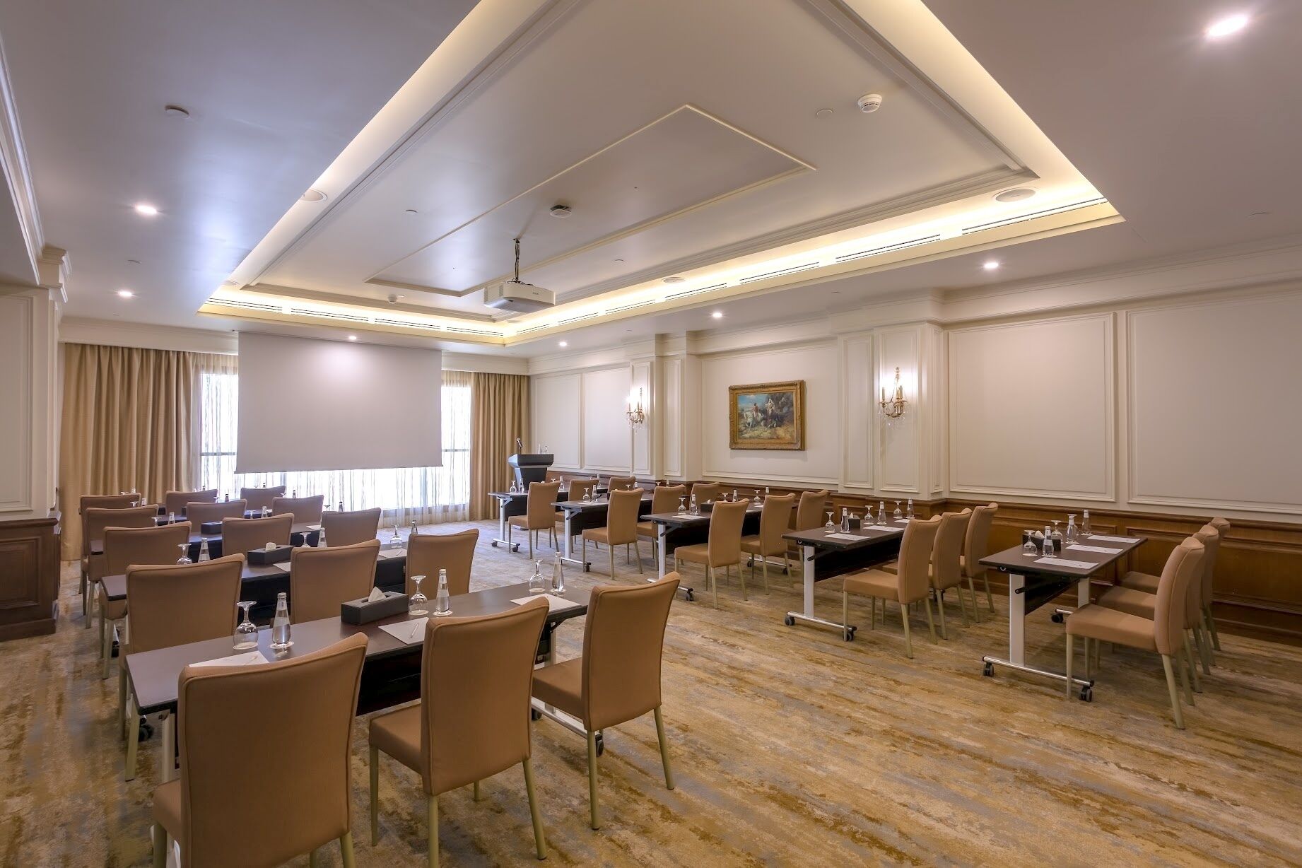 A conference room with multiple tables and chairs, equipped with microphones and water bottles.