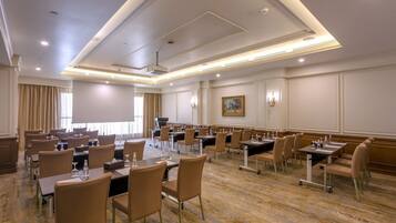A conference room with multiple tables and chairs, equipped with microphones and water bottles.