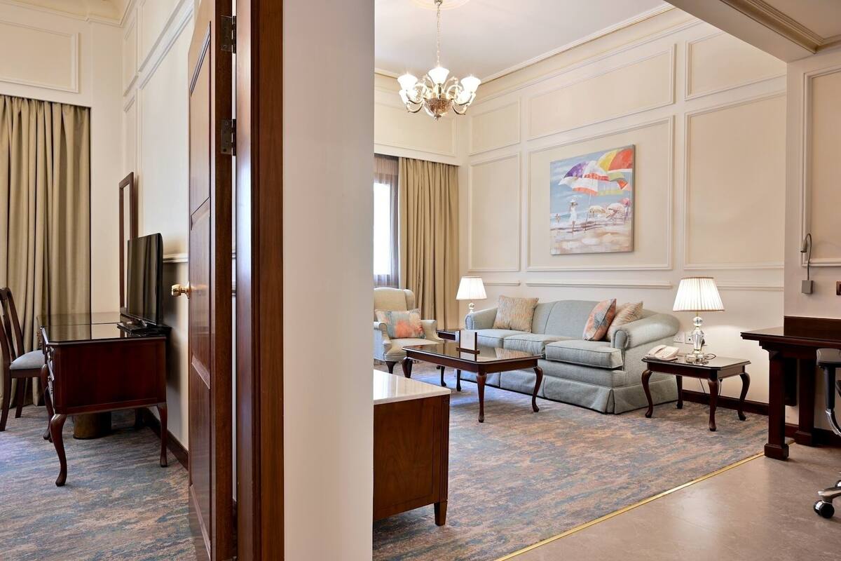 Una sala de estar elegante con televisión, un conjunto de sofás, una mesa de centro y una araña.