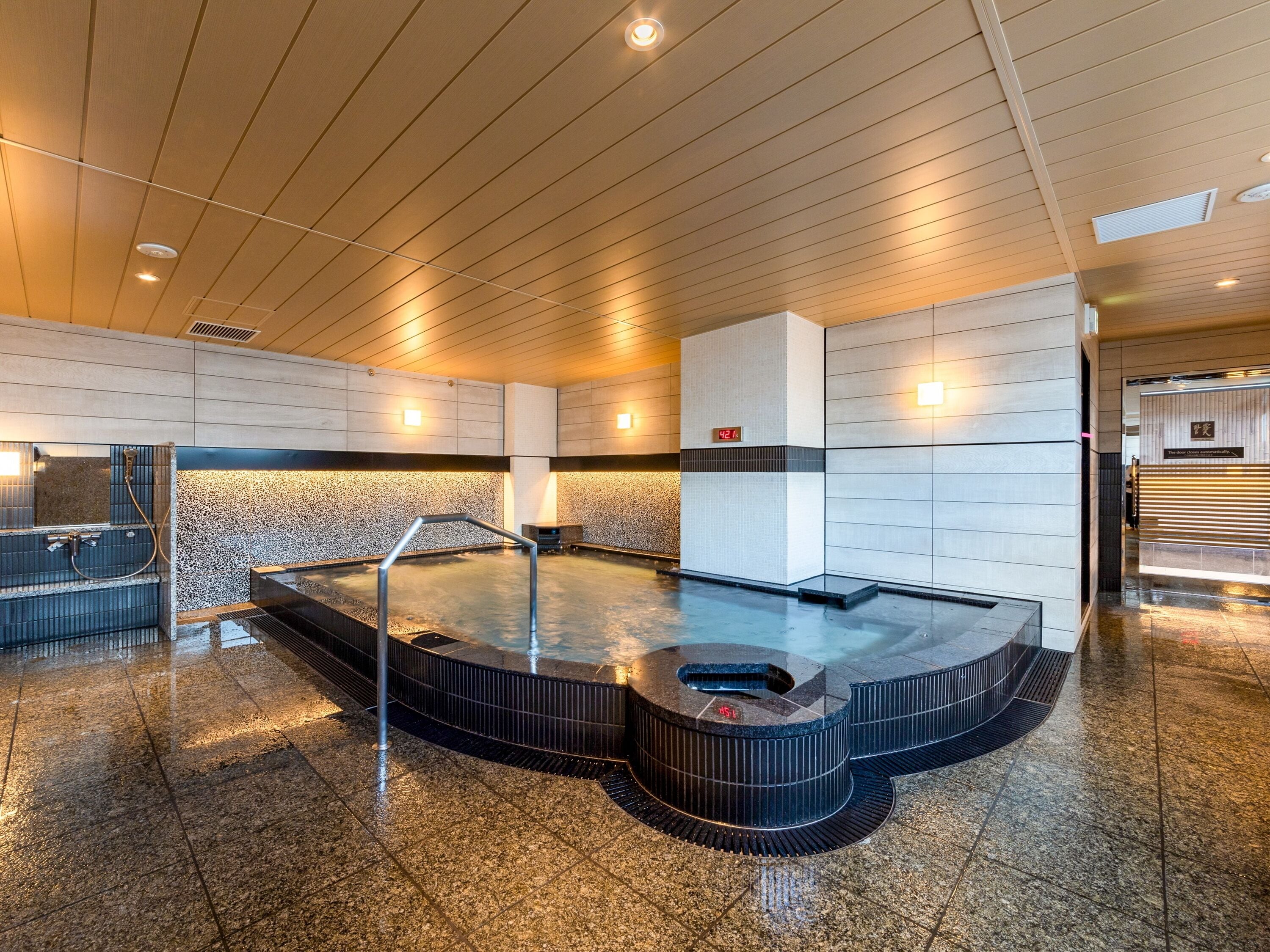 A modern spa area with a hot tub, a digital clock, and a reception desk.