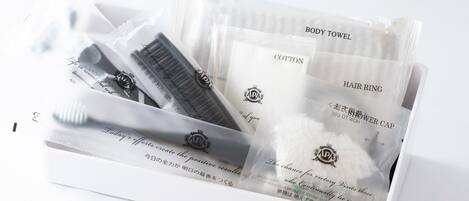 A white toiletry set with items like a body towel, cotton, hair ring, and shower cap.