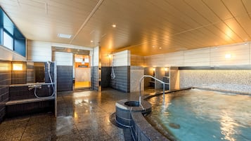 Un área de piscina interior moderna con un jacuzzi, un vestuario y zona de duchas.
