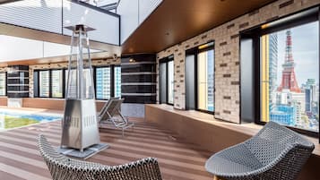 A modern indoor space with a pool, lounge chairs, and large windows offering a city view.
