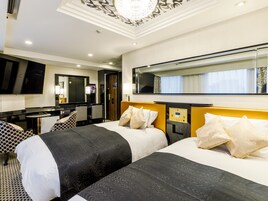 A hotel room with two beds, a desk, a chair, and a large mirror.