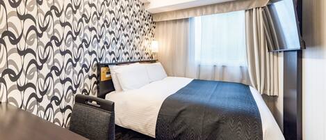 Habitación de hotel con cama, escritorio, silla, televisor y pared con diseño.