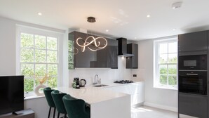 Cozinha moderna com uma ilha grande, banquetas, televisão e forno embutido.