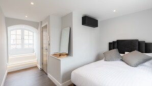 Quarto com cama, um espelho grande, prateleira embutida e janela com vista.