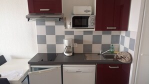 Eine kompakte Küche mit Mikrowelle, Kaffeemaschine und Geschirrspüler.