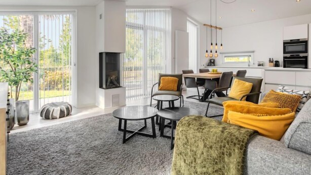 Un salon moderne avec un canapé gris, une table basse et un coin repas comprenant des chaises et une table.
