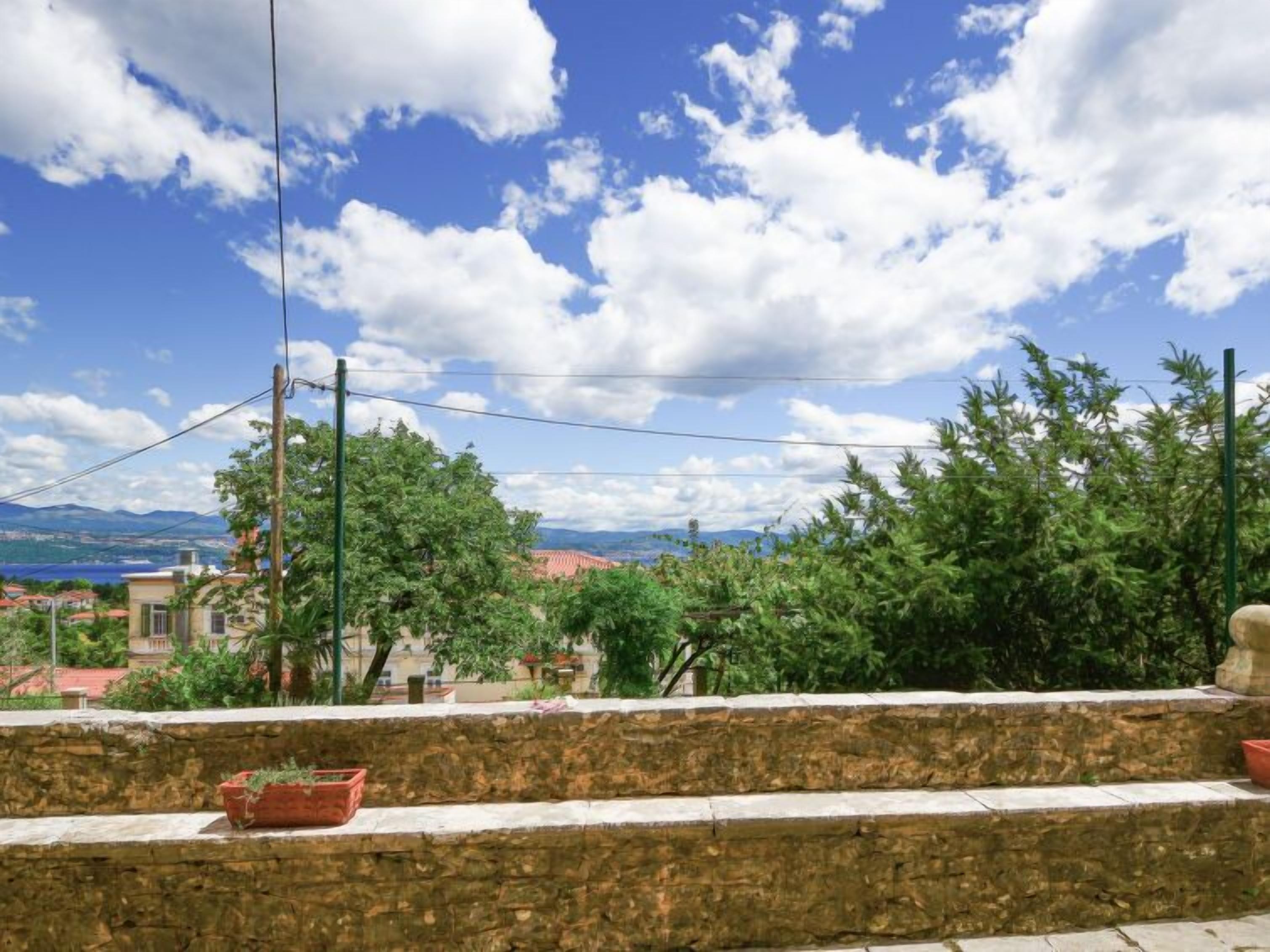 Un mur de pierre agrémenté de plantes en pot, avec une vue sur une ville et des montagnes au loin.