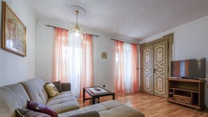 Una sala de estar con un sofá, una mesa de centro, un televisor sobre un mueble de madera y puertas decoradas.