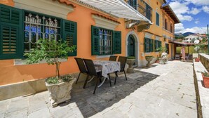 Un edificio tradicional con un patio empedrado, mobiliario exterior y una pequeña zona ajardinada.