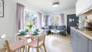 A modern kitchen with a coffee maker, a kettle, and a dining area with a table set for four.