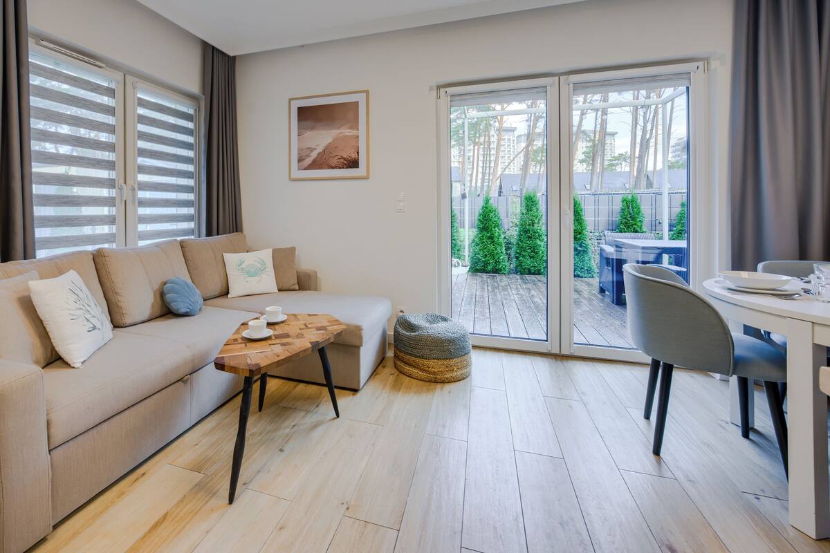 A modern living room with a sofa, a wooden coffee table, and a dining area with a table and chairs.