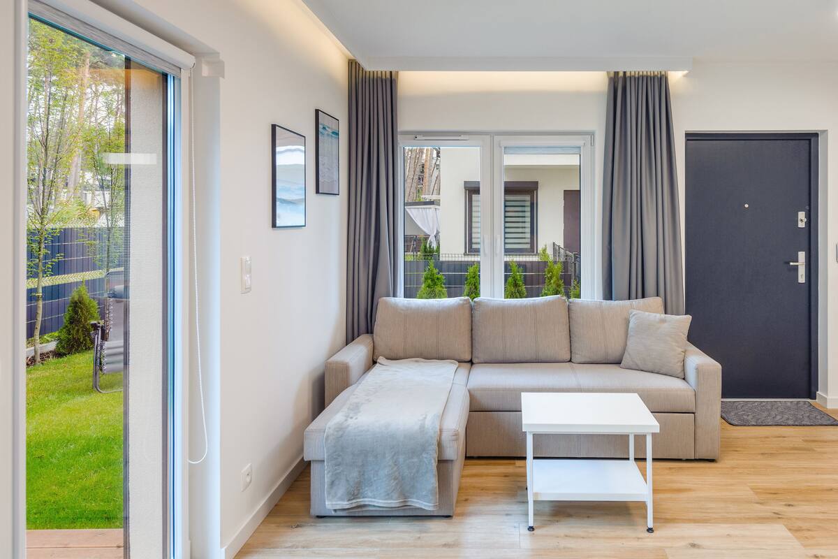 A modern living room with a sofa, a small table, and a door leading to a staircase.