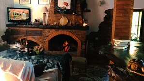 A cozy living room with a fireplace, a television, and a dining area with a table set for two.