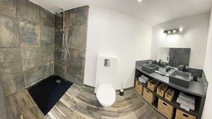 Un baño moderno con ducha, inodoro y lavamanos dobles.
