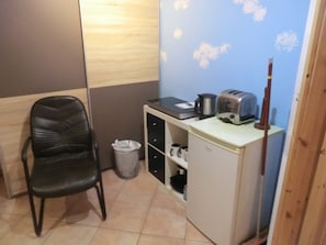 Cozy retreat with a kitchenette, featuring a comfortable chair, refrigerator, coffee maker, and toaster.