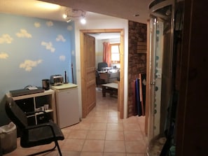 Cozy room with a kitchenette area, featuring a refrigerator and toaster, and a separate room accessible through a wooden door.
