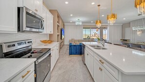 Une cuisine moderne avec des meubles blancs, des appareils en acier inoxydable et un îlot central.